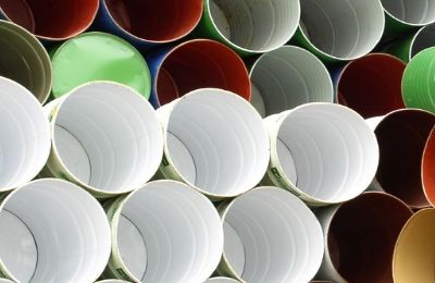 Empty industrial drums stacked mouth-upward, lined in white, green and red.